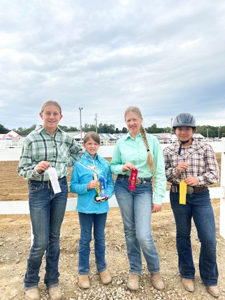 Four participants in the morrow county horse and pony show hold up their ribbons and awards